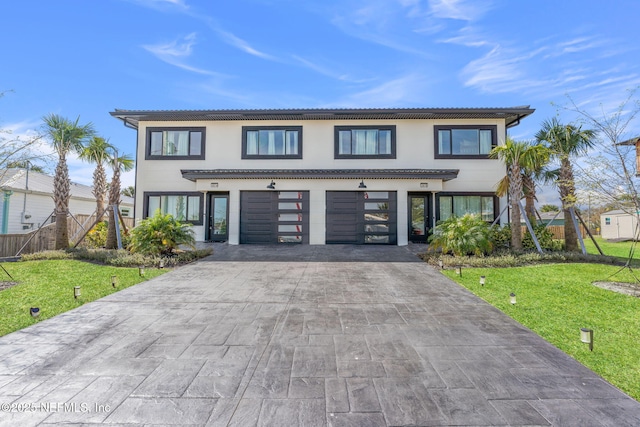 view of front of property featuring a garage, a front lawn, decorative driveway, and stucco siding