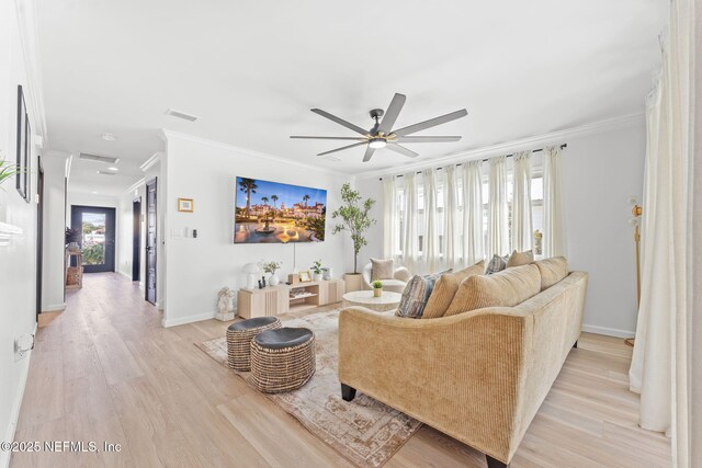 living area with visible vents, light wood-style flooring, ornamental molding, a ceiling fan, and baseboards