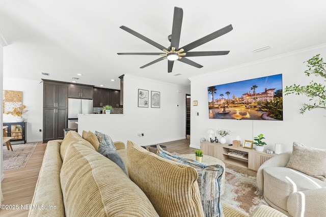 living area featuring ceiling fan, light wood-type flooring, and crown molding