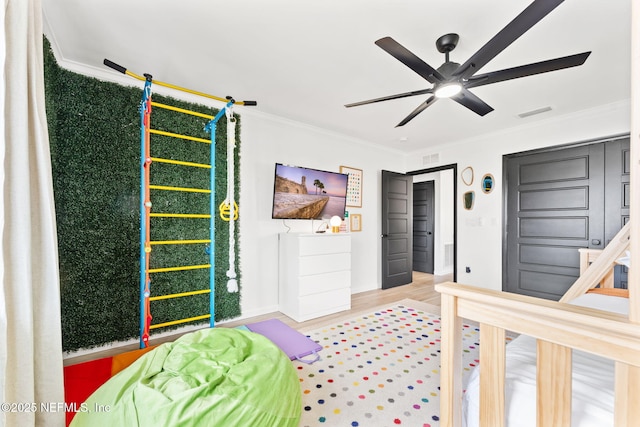 bedroom with baseboards, visible vents, ceiling fan, wood finished floors, and crown molding