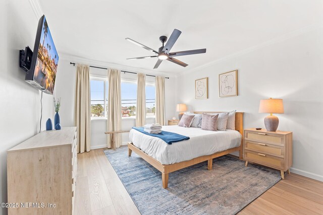 bedroom with light wood-style floors, crown molding, baseboards, and a ceiling fan