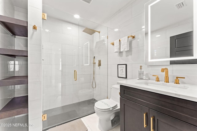 full bath with a stall shower, visible vents, toilet, vanity, and tile walls