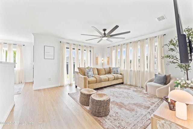 living area featuring crown molding, visible vents, light wood-style flooring, ceiling fan, and baseboards