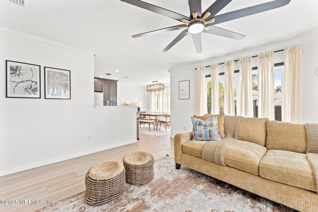 living room featuring baseboards, light wood finished floors, a ceiling fan, and crown molding