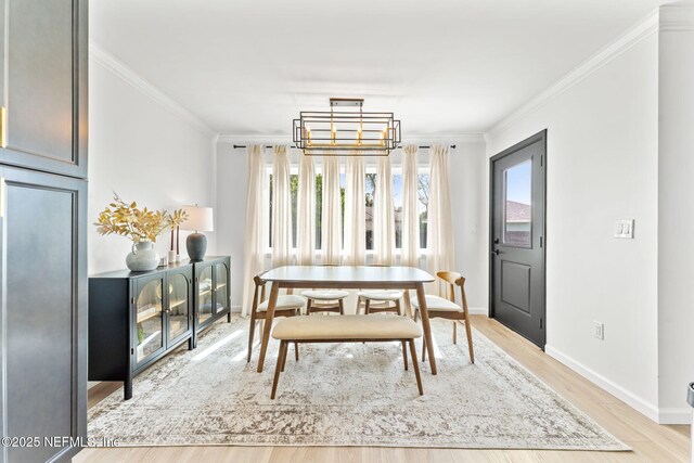 dining space featuring crown molding, baseboards, a chandelier, and light wood-style floors