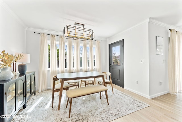 dining room with a chandelier, crown molding, baseboards, and wood finished floors