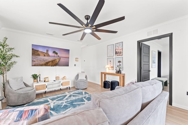 living room with light wood finished floors, ceiling fan, visible vents, and crown molding