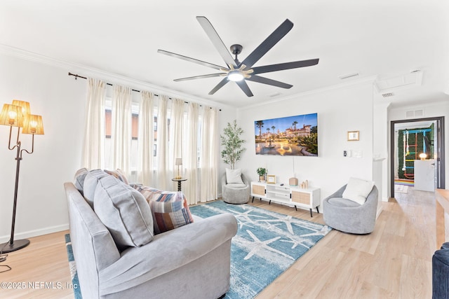 living area featuring ceiling fan, wood finished floors, visible vents, baseboards, and crown molding