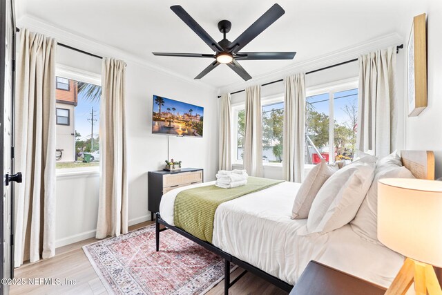 bedroom featuring baseboards, ceiling fan, light wood-type flooring, and crown molding