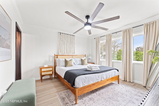 bedroom with baseboards, ceiling fan, ornamental molding, and light wood-style floors