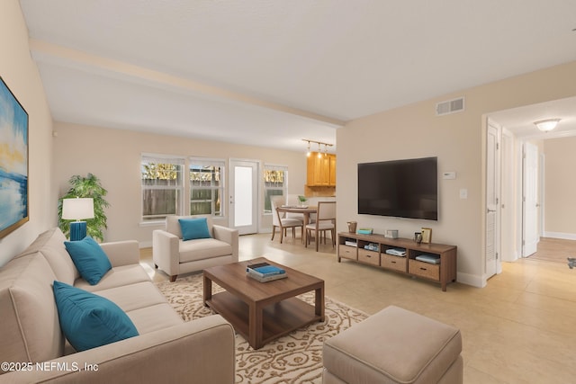 living area featuring light tile patterned floors, visible vents, and baseboards