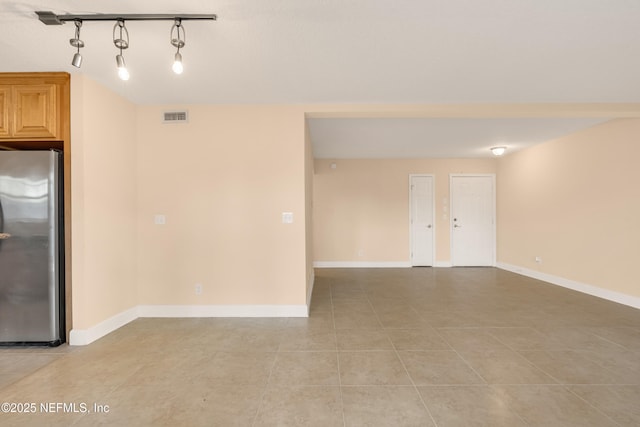 spare room featuring baseboards, visible vents, and light tile patterned flooring