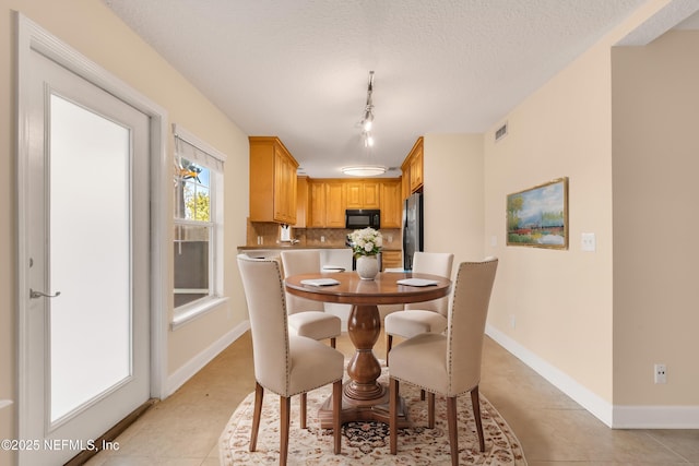 dining room with light tile patterned floors, baseboards, visible vents, and a textured ceiling