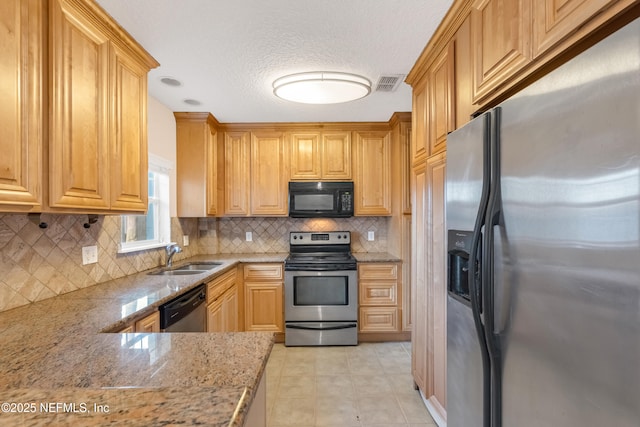 kitchen featuring light stone counters, backsplash, appliances with stainless steel finishes, light tile patterned flooring, and a sink