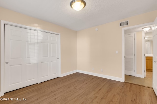 unfurnished bedroom with light wood-type flooring, baseboards, visible vents, and a textured ceiling