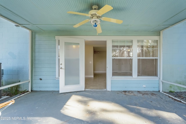 view of exterior entry with concrete block siding, ceiling fan, and a patio