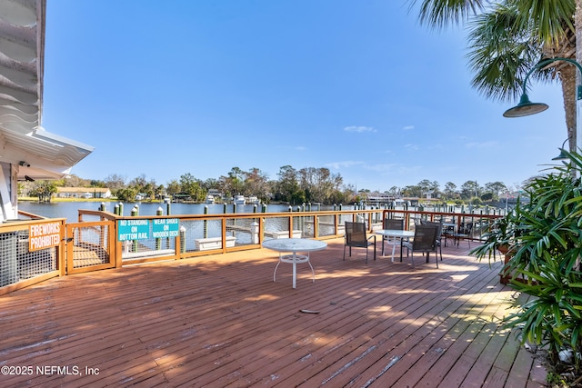 wooden deck with a water view and outdoor dining space