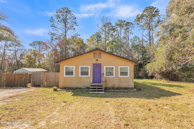 bungalow with entry steps, fence, and a front yard