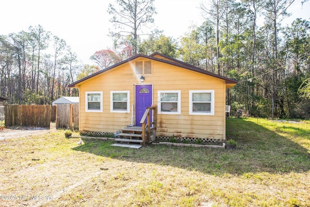 bungalow featuring a front lawn and fence