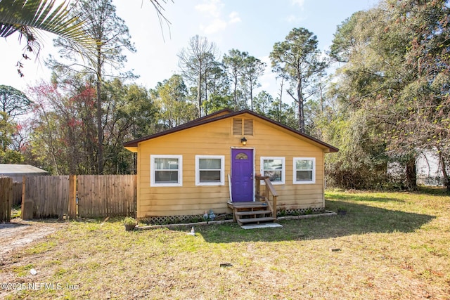 bungalow-style house featuring entry steps, fence, and a front lawn