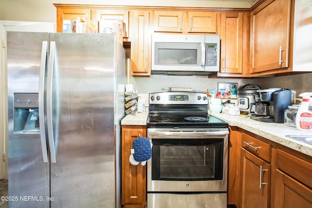 kitchen featuring appliances with stainless steel finishes, brown cabinetry, and light countertops