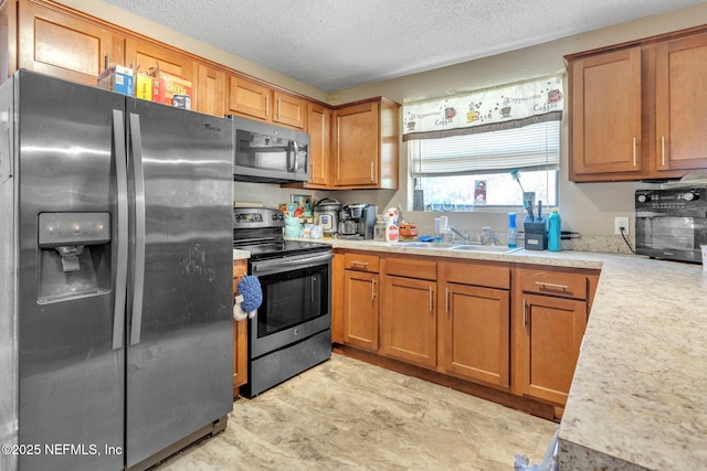 kitchen with stainless steel appliances, a sink, light countertops, and brown cabinets