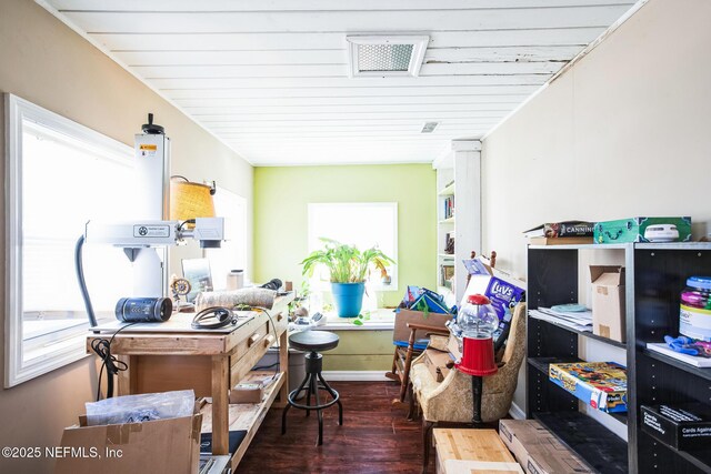 interior space with baseboards, wood finished floors, visible vents, and a healthy amount of sunlight