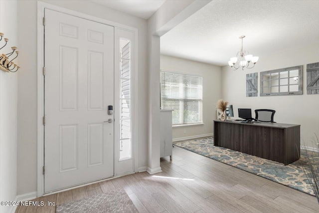 entrance foyer with a chandelier, baseboards, and wood finished floors