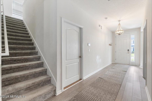 foyer with a textured ceiling, stairway, wood finished floors, and baseboards