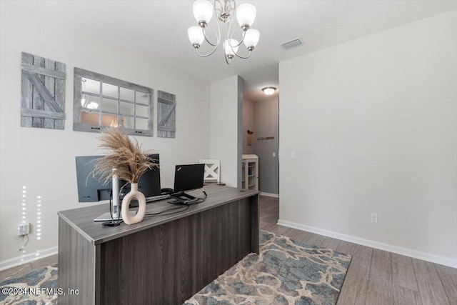 office area featuring baseboards, visible vents, a chandelier, and wood finished floors