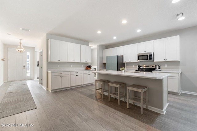 kitchen featuring a breakfast bar, stainless steel appliances, light countertops, visible vents, and white cabinetry