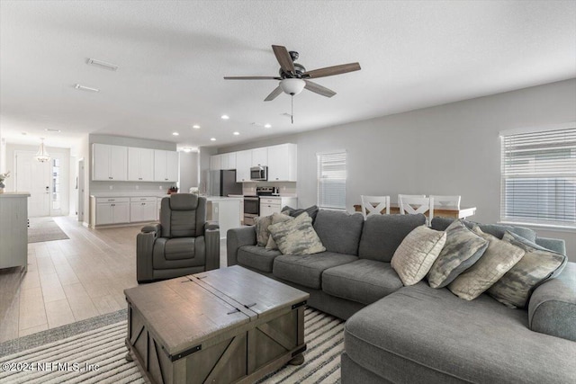 living area featuring plenty of natural light, a textured ceiling, visible vents, and a ceiling fan