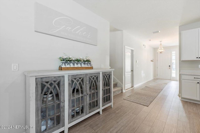 hall with stairs, light wood-type flooring, and baseboards