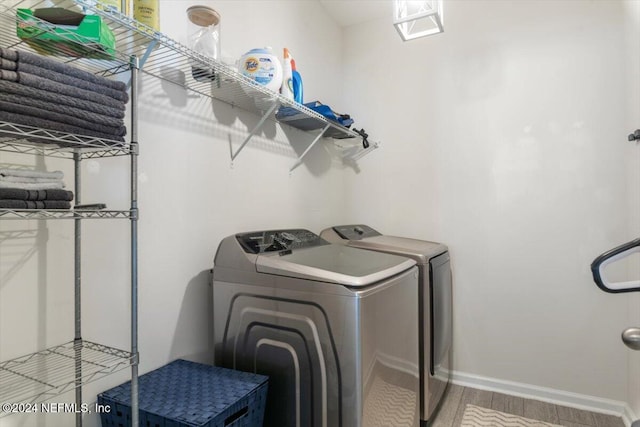 laundry room with laundry area, washer and clothes dryer, baseboards, and wood finished floors