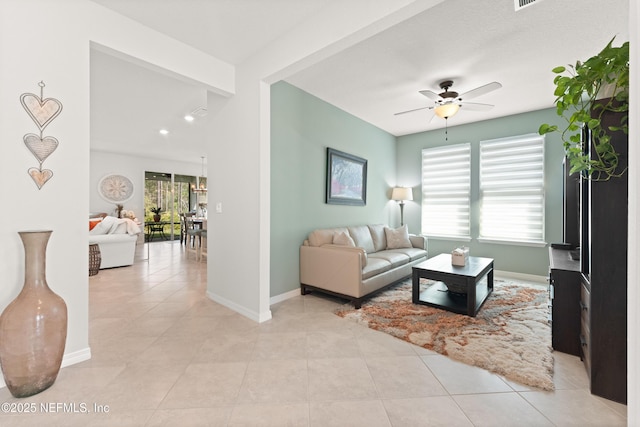 living area with light tile patterned flooring, ceiling fan, and baseboards