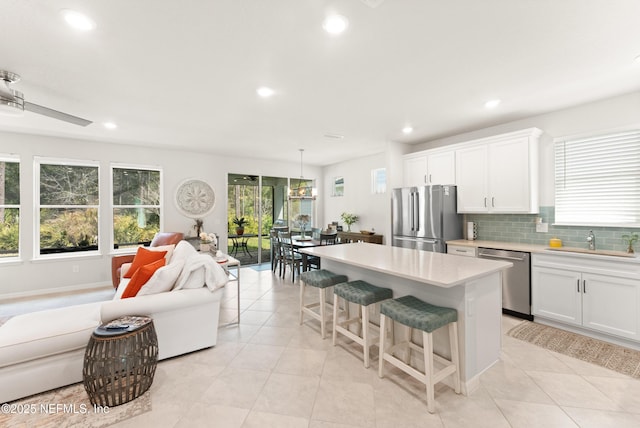 kitchen featuring decorative backsplash, a kitchen breakfast bar, stainless steel appliances, light countertops, and a sink