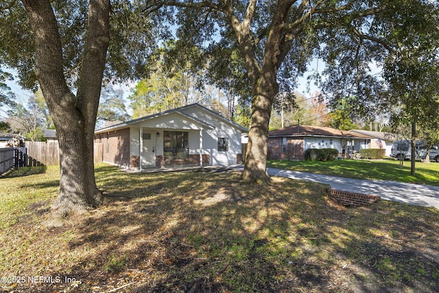 view of front of home with brick siding, fence, covered porch, and a front yard