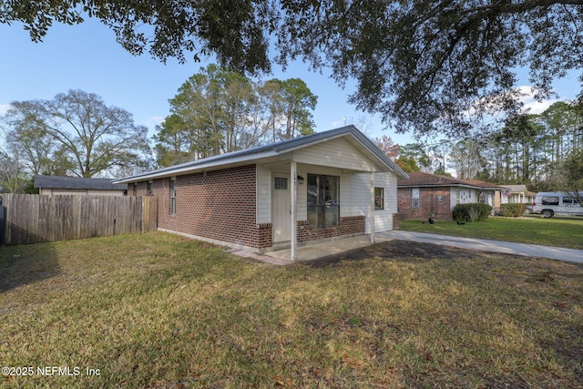 view of front facade featuring brick siding, fence, and a front lawn