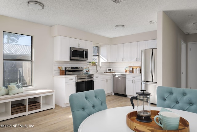 kitchen featuring light wood finished floors, appliances with stainless steel finishes, and white cabinetry