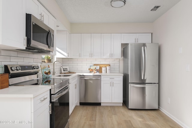 kitchen featuring visible vents, appliances with stainless steel finishes, white cabinets, and a sink