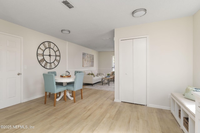 dining room with light wood-type flooring, visible vents, and baseboards