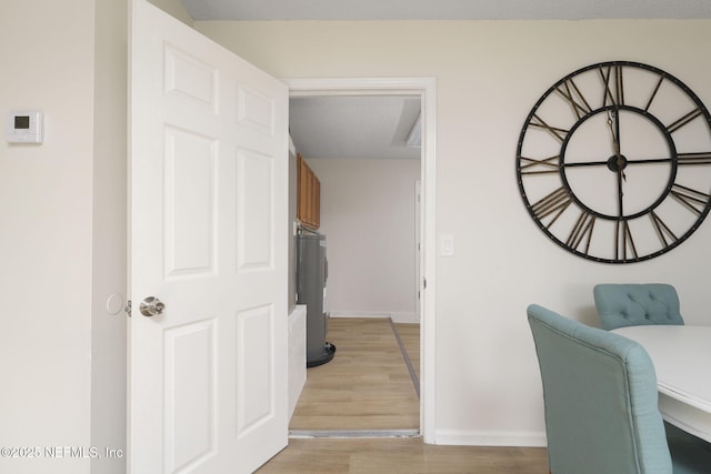 hallway featuring light wood finished floors and baseboards