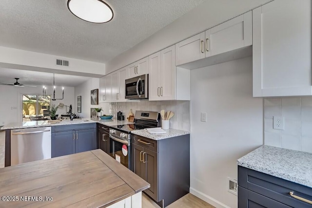 kitchen featuring stainless steel appliances, visible vents, backsplash, white cabinets, and a sink