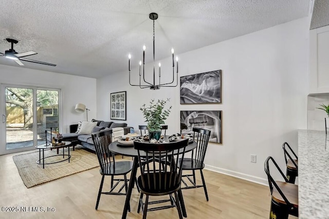 dining area featuring a textured ceiling, light wood finished floors, a ceiling fan, and baseboards