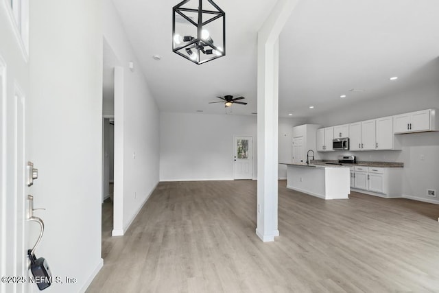 kitchen with open floor plan, appliances with stainless steel finishes, light wood-style flooring, and white cabinetry