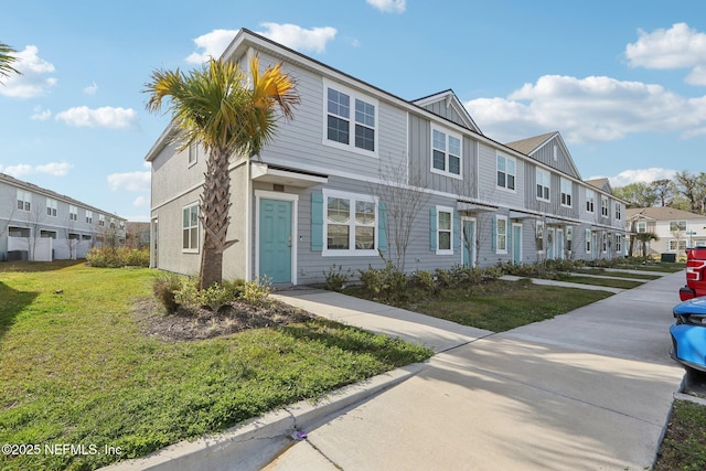 view of property featuring board and batten siding, a front yard, and a residential view