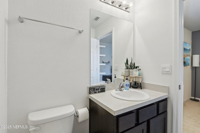 bathroom featuring toilet, vanity, and visible vents