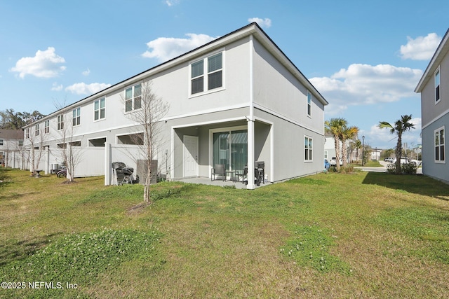 back of house with stucco siding, a yard, and a patio