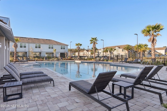 pool with a residential view, a patio area, and fence