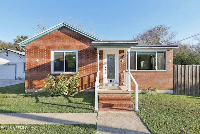 bungalow featuring brick siding, an outdoor structure, a front lawn, and fence